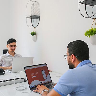 Two Chari team members working on laptops in the office, one screen showing the Chari app